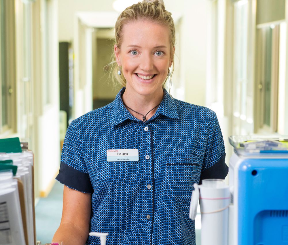 Eldercare Clinical Leader Laura smiling at the camera from behind a medication trolley.