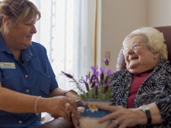 An Eldercare lifestyle support staff member gives a resident a pot filled with lavender.