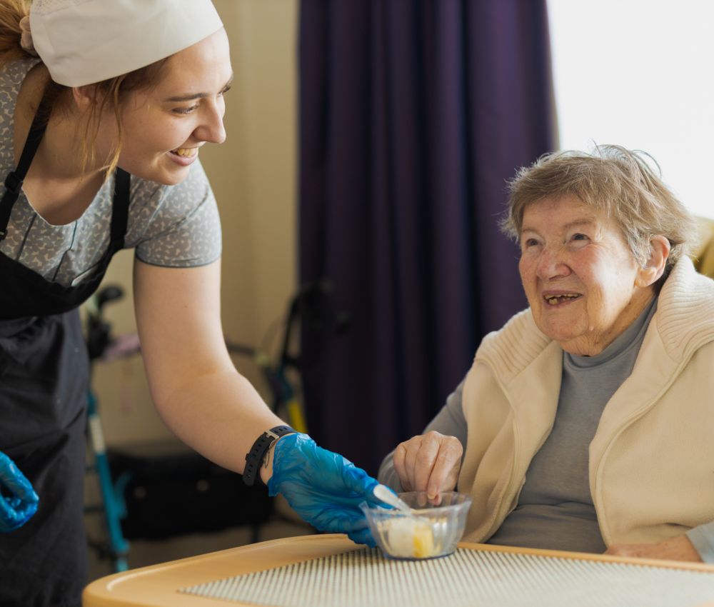 An Eldercare resident is served some afternoon tea by a hospitality assistant.
