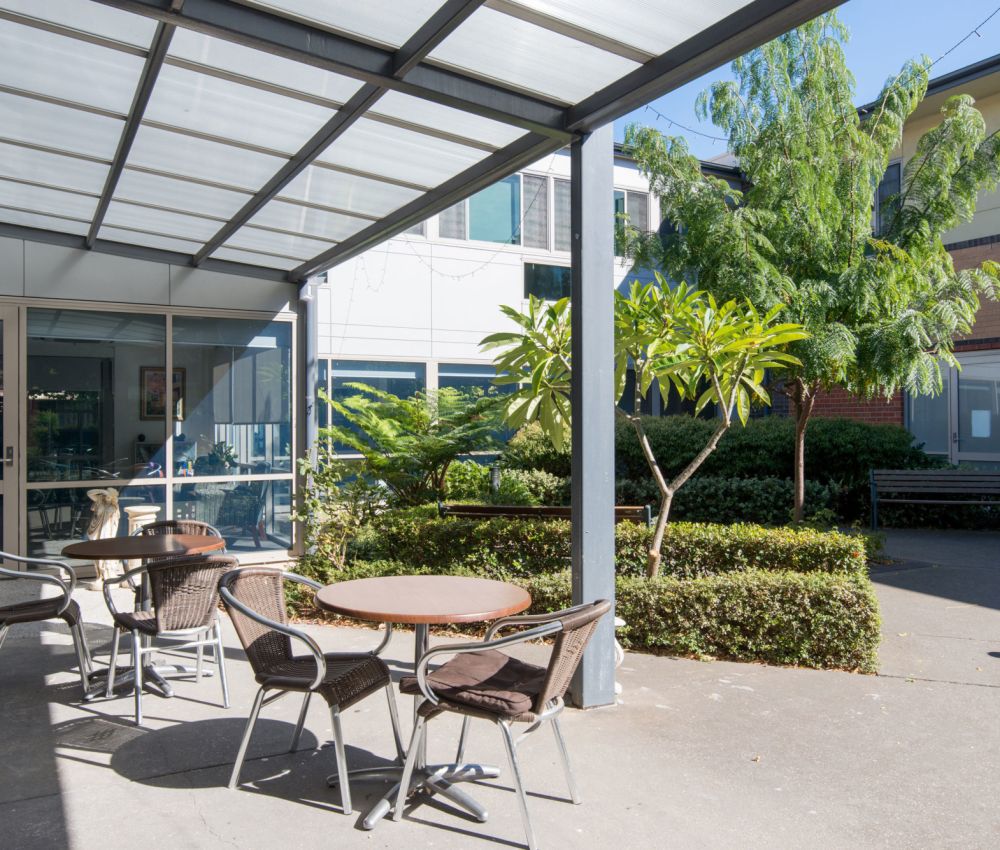 Eldercare Allambi outdoor area with dining set and green trees.