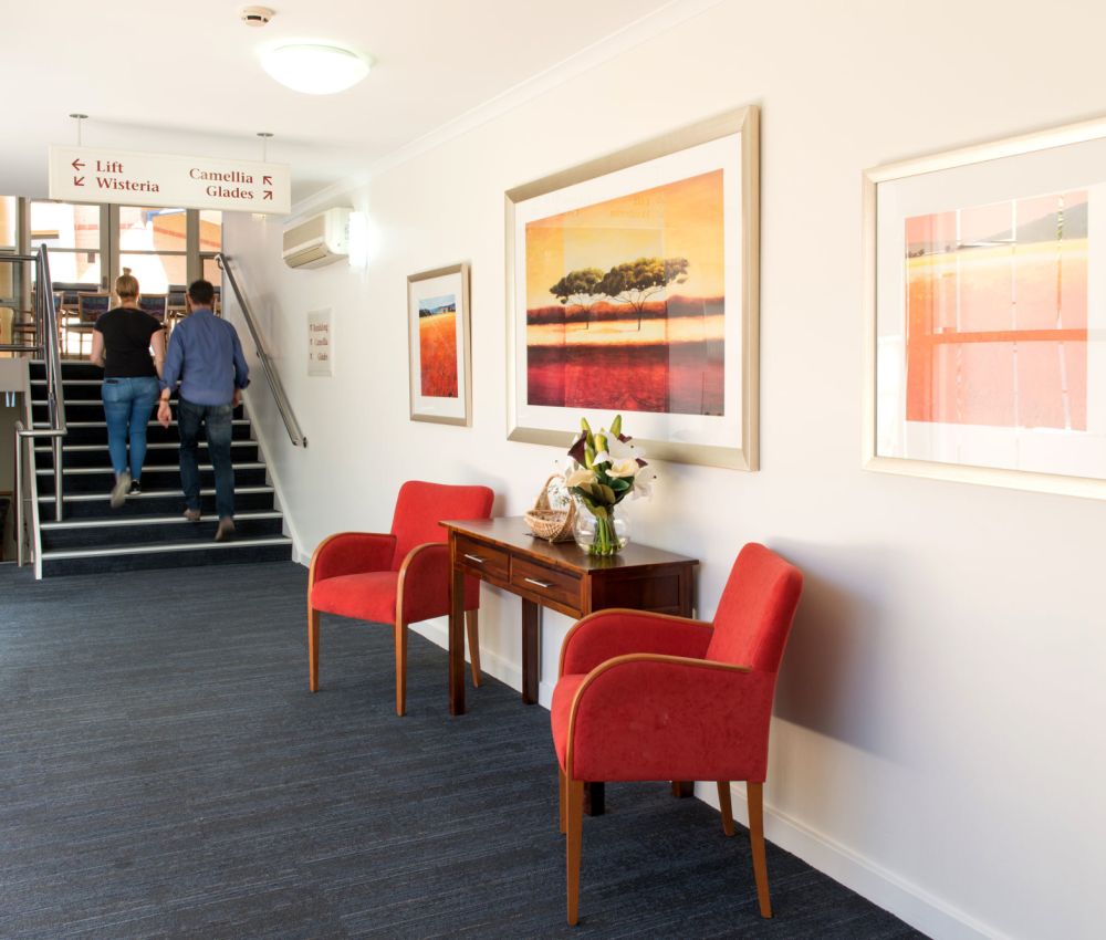Lounge area at Eldercare Cottage Grove with armchairs and a bunch of flowers in a vase.