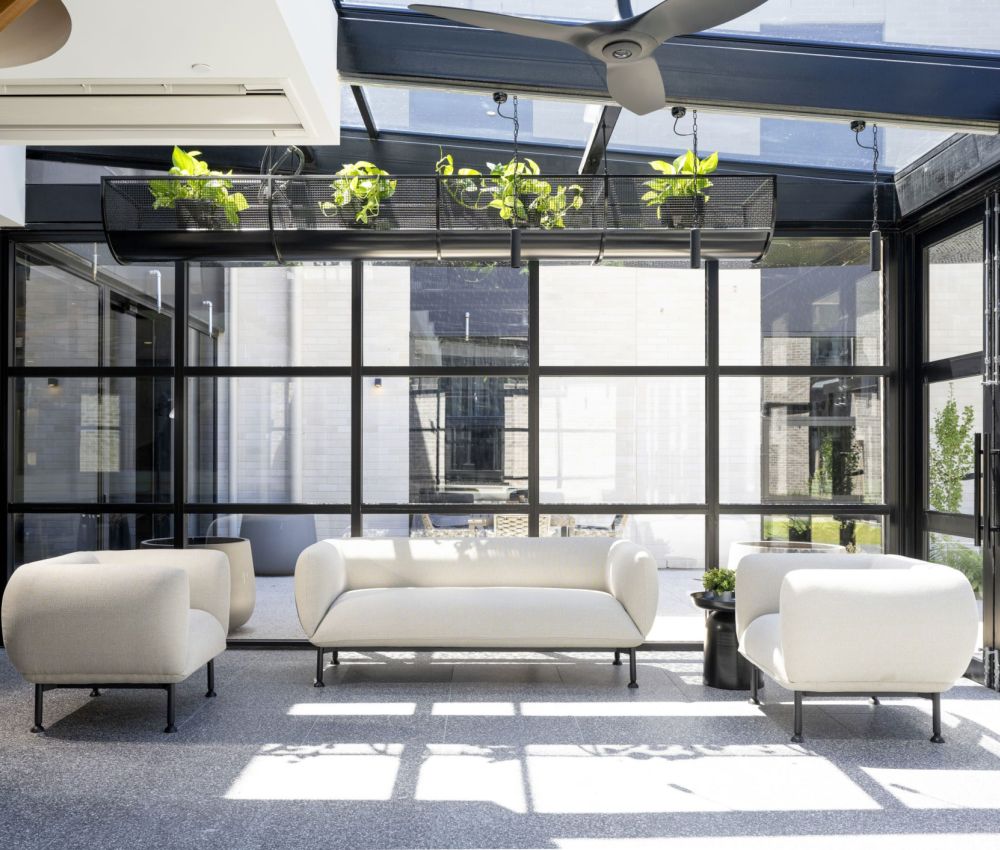 Stylish conservatory patio with white furniture and vibrant plants, offering a contemporary and inviting atmosphere.