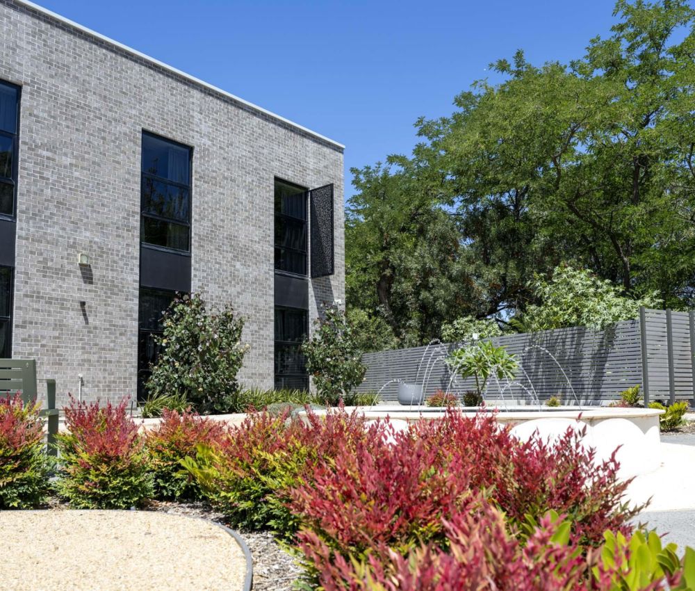 A secure garden at Eldercare Goodwood aged care site, featuring a courtyard surrounded by lush greenery and plants.