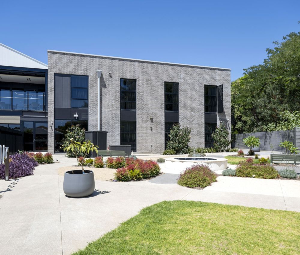 A secure garden at Eldercare Goodwood aged care site, featuring a courtyard surrounded by lush greenery and plants.