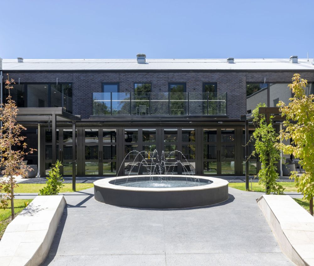 A serene courtyard garden featuring a fountain and a cozy patio area at Eldercare Goodwood aged care.