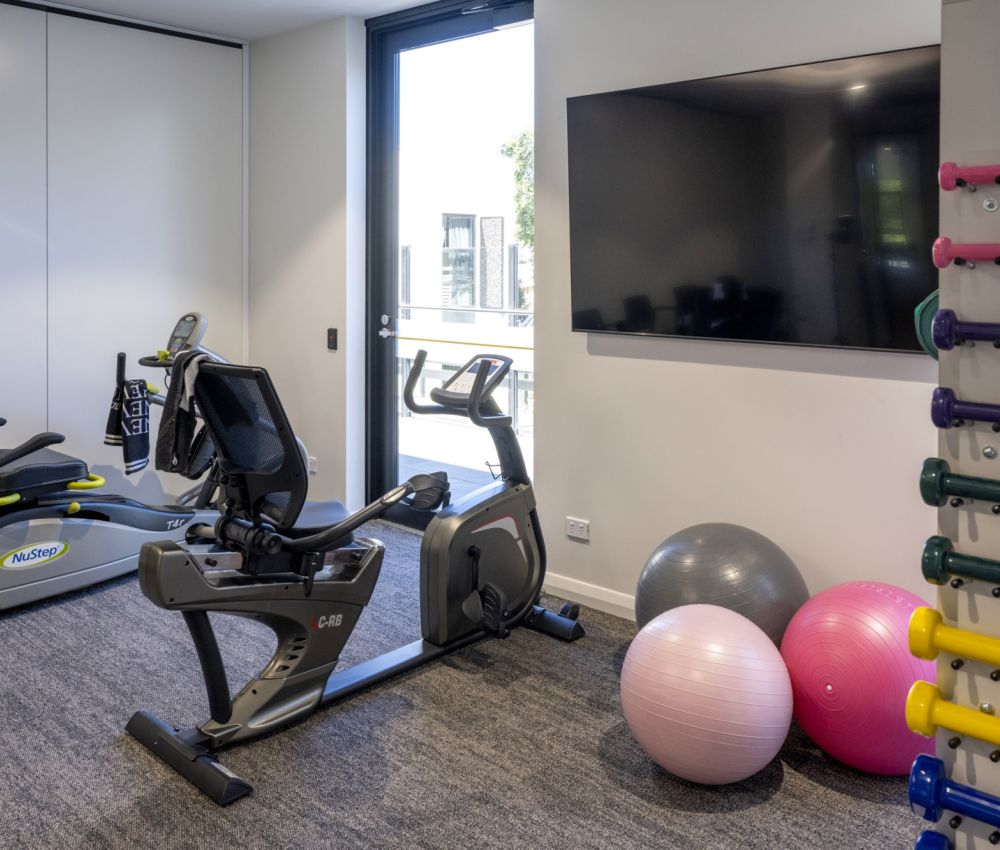 Exercise equipment and a television in a gym room at Eldercare Goodwood aged care site, promoting health and wellness for residents.