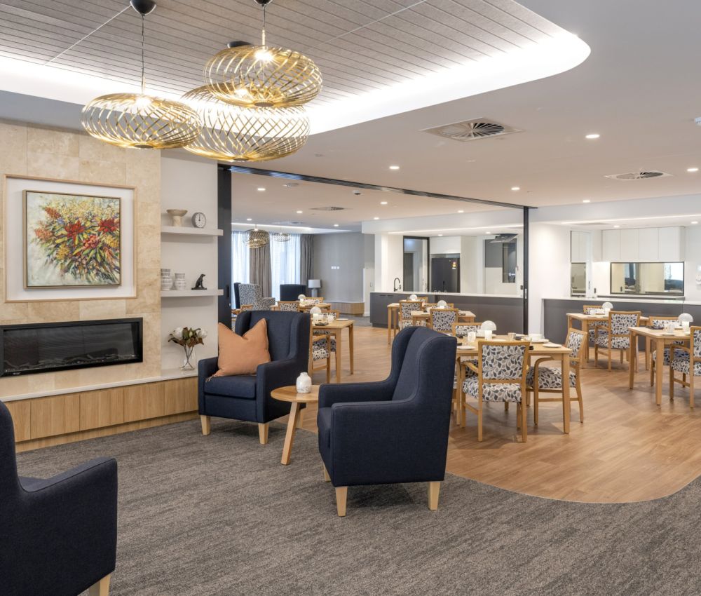 A modern dining room featuring stylish chairs and tables, designed for a comfortable lounge and dining area at Eldercare Goodwood aged care.