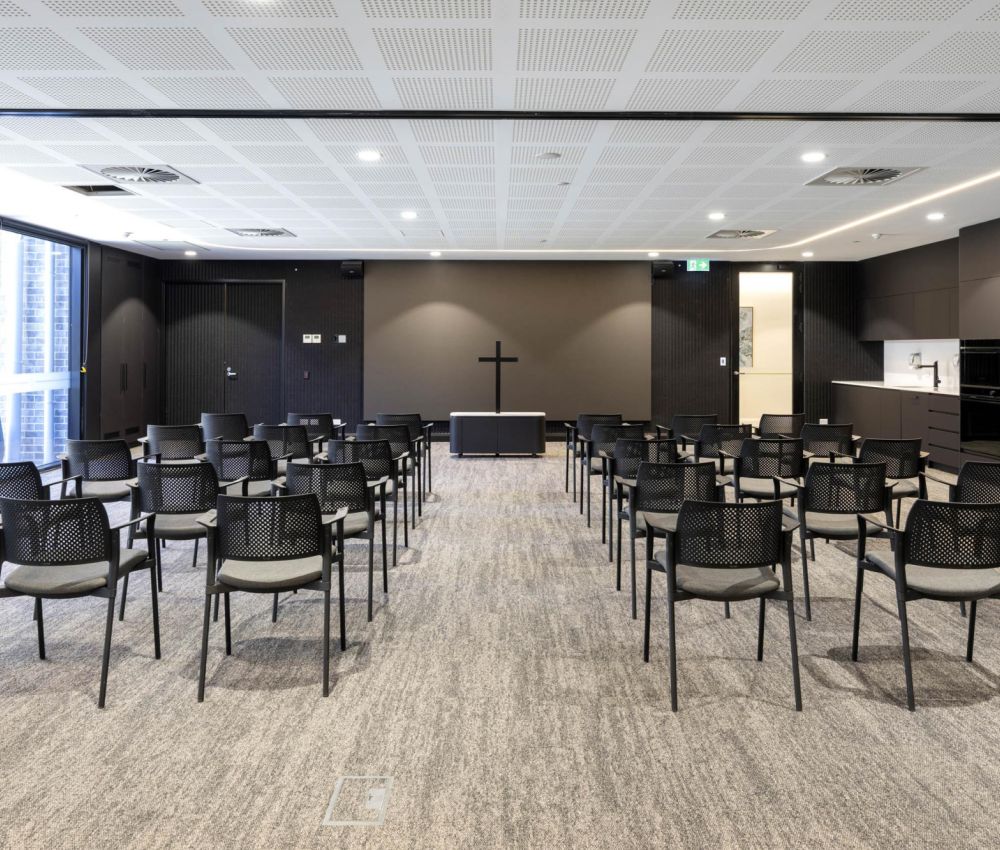 A spacious multi-purpose theatre room at Eldercare Goodwood aged care, featuring chairs and a TV on the wall.