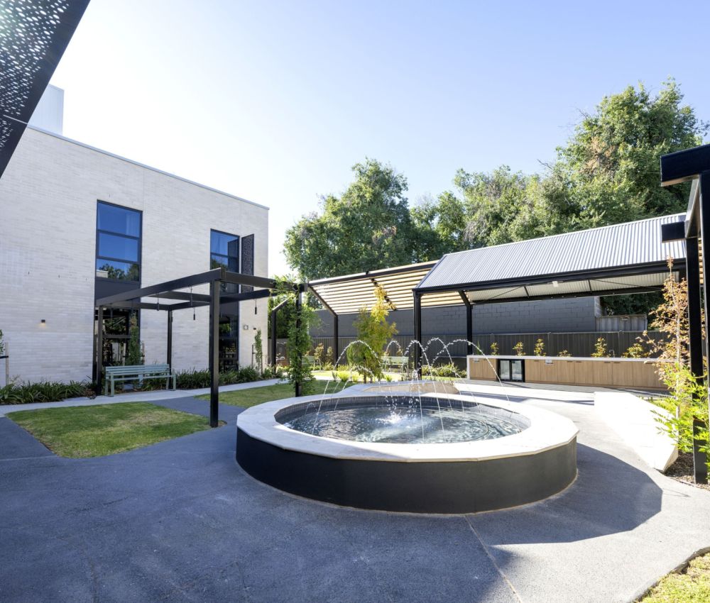 A serene courtyard garden featuring a fountain and a cozy patio area at Eldercare Goodwood aged care.