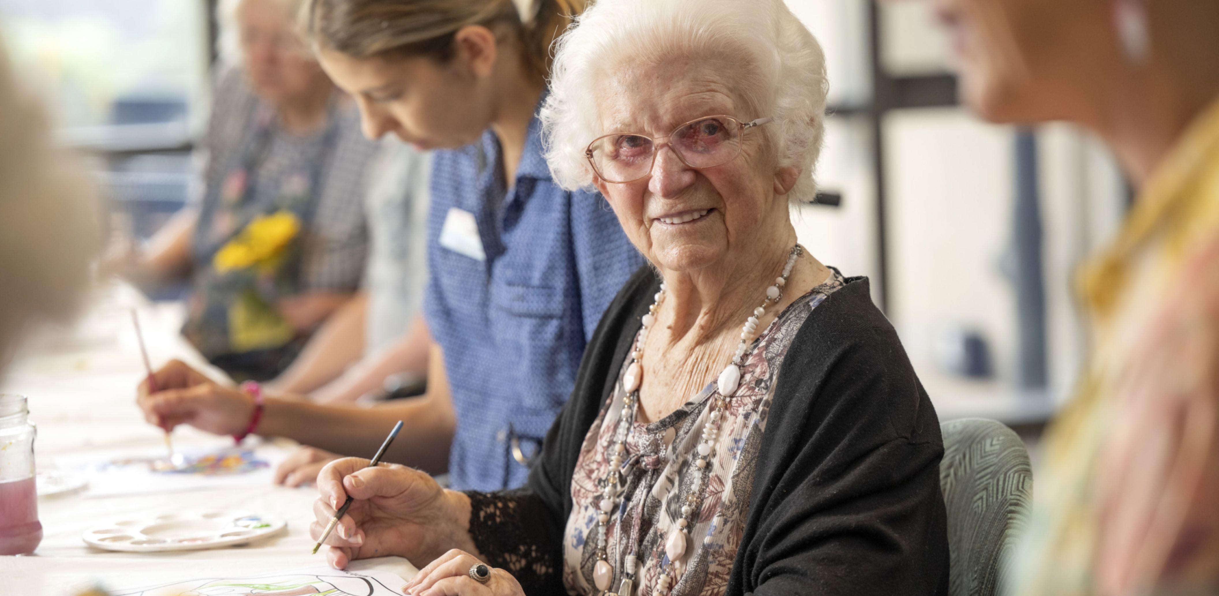 A group of Eldercare residents engages in a painting activity, fostering community and artistic expression.