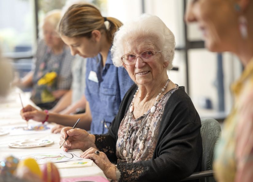 A group of Eldercare residents engages in a painting activity, fostering community and artistic expression.