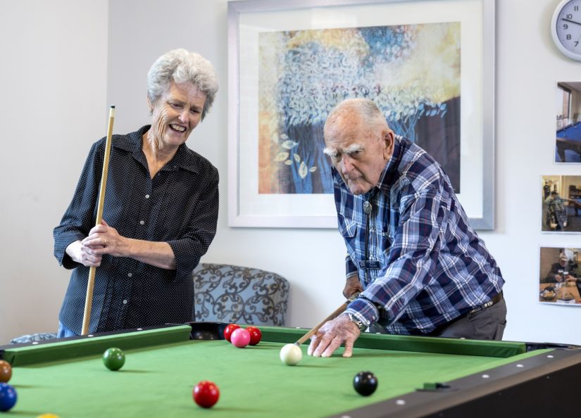 An Eldercare resident and a woman playing pool together.