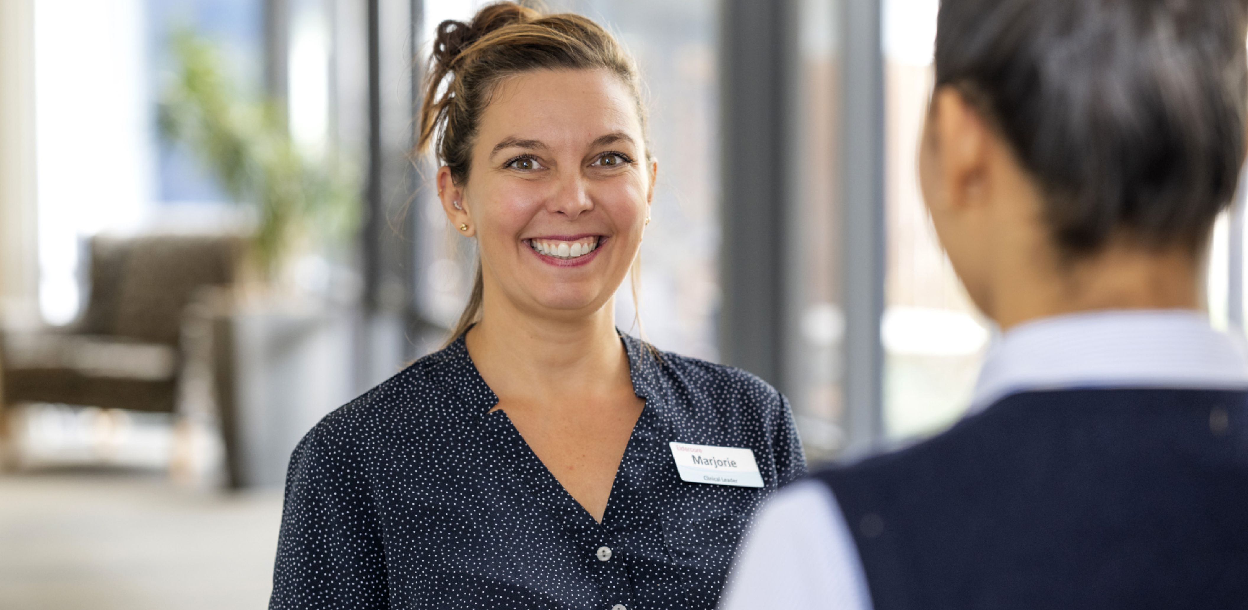 Two Eldercare staff members engage in conversation in the hallway.