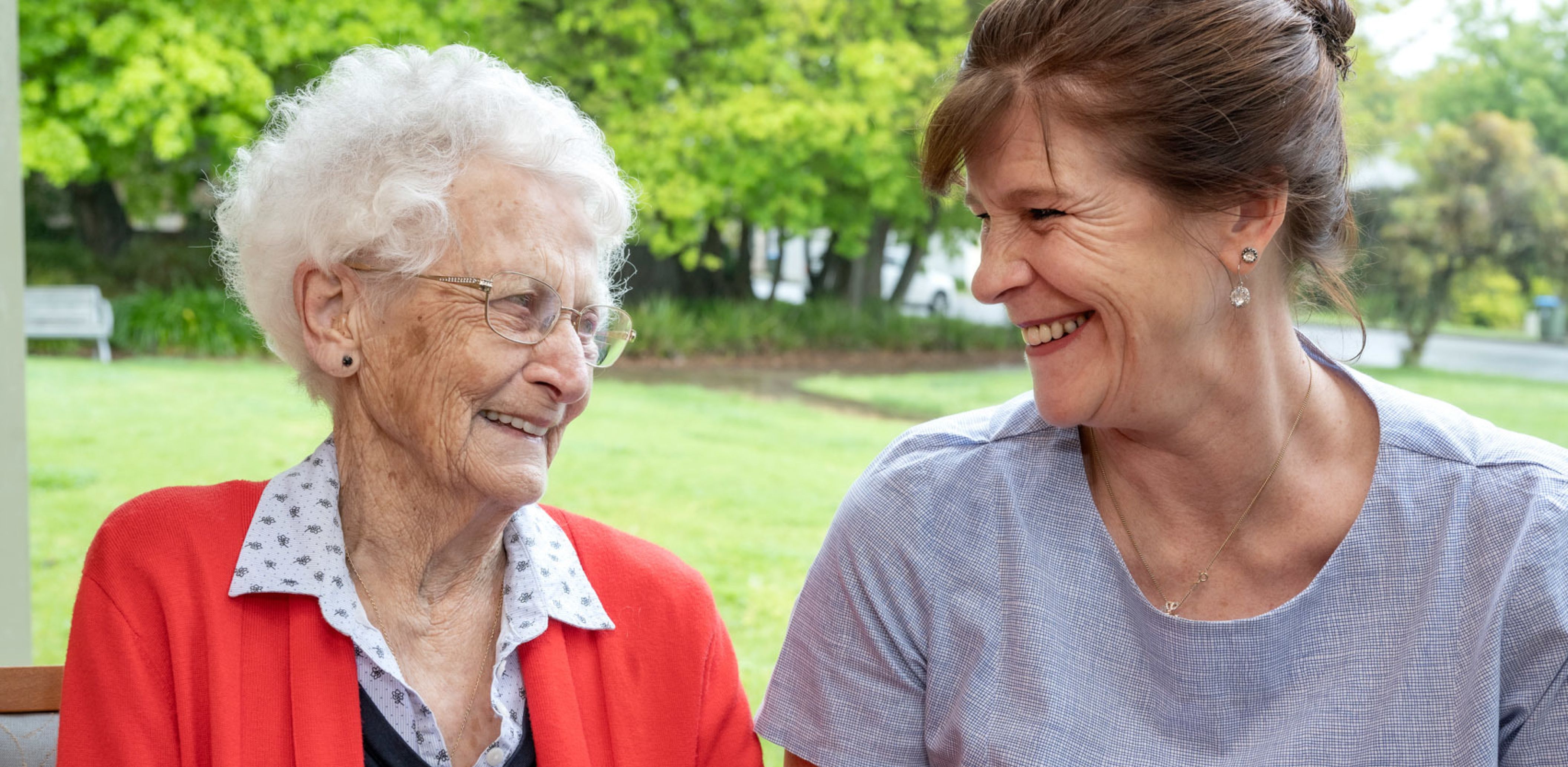 An Eldercare Care Assistant and a resident smiling at each other.