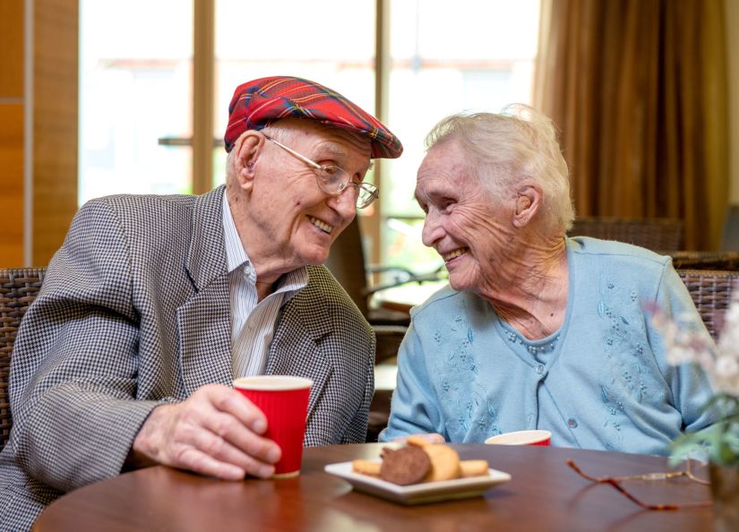 Eldercare residents Clem and Dot smiling at each other.
