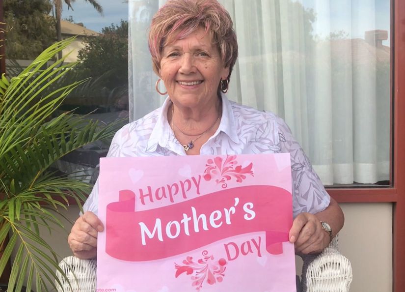Eldercare Oxford resident holding a Mother's day card and smiling at the camera.