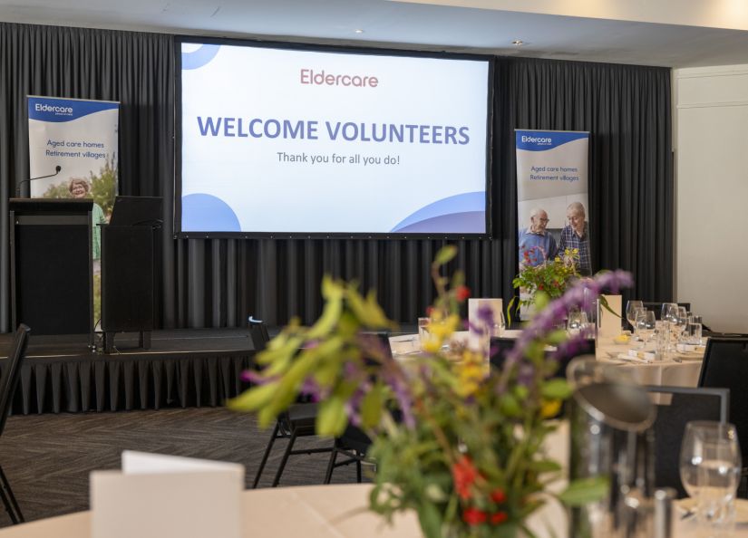 A welcoming room featuring tables and chairs organised for an event to greet volunteers.