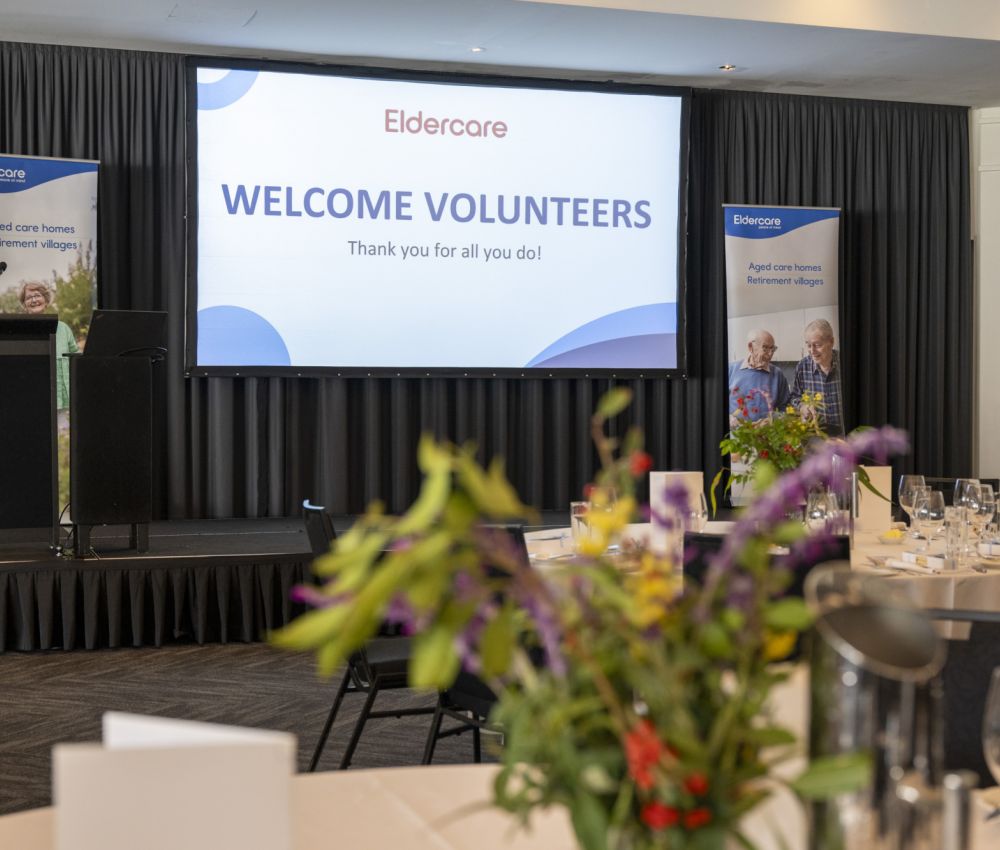 A welcoming room featuring tables and chairs organised for an event to greet volunteers.