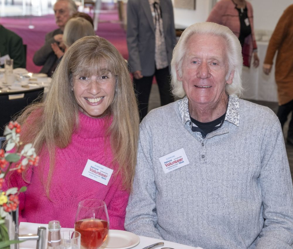 A female and a male volunteer smiling at the camera.