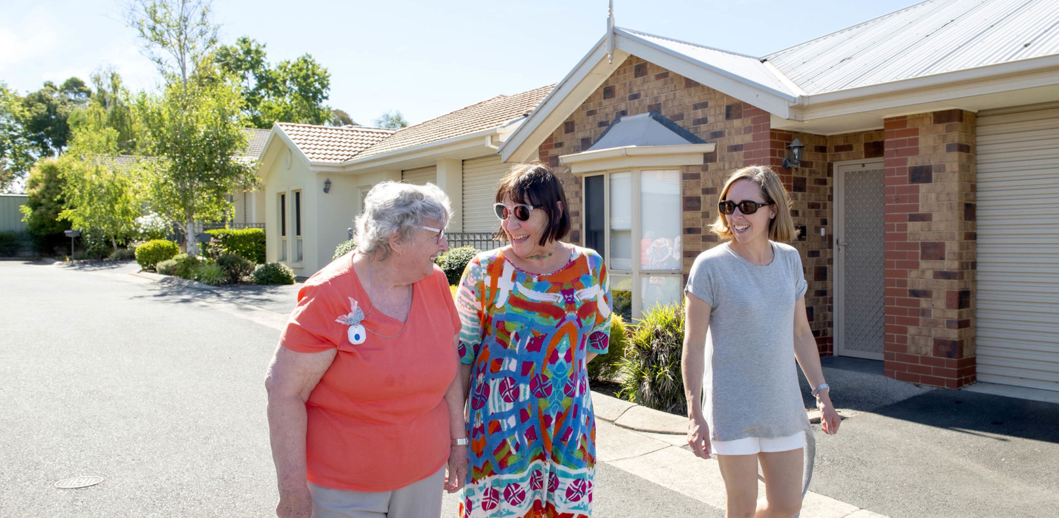Eldercare Exhibition Court Retirement Living residents and family members walking and smiling at each other.