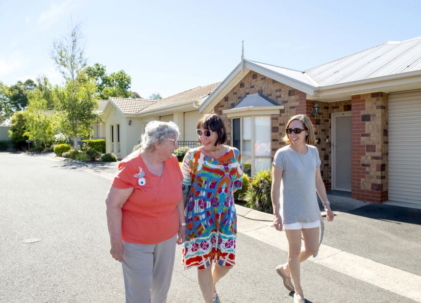 Eldercare Exhibition Court Retirement Living residents and family members walking and smiling at each other.