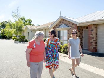 Eldercare Exhibition Court Retirement Living residents and family members walking and smiling at each other.