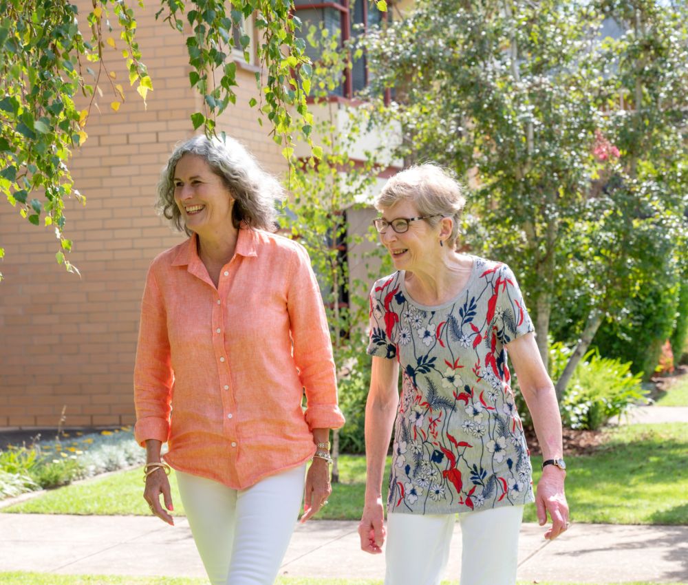 Eldercare Elmwood Grove Retirement Living resident and family member walking and smiling.
